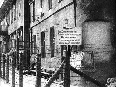 Вывеска с запрещающей надписью над ограждением из колючей проволоки на территории Минского гетто